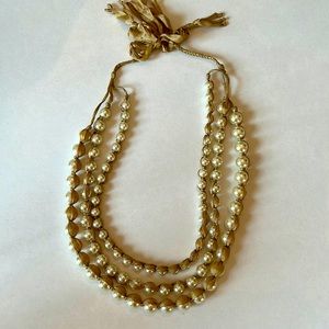 Tripe strand pearl necklace wrapped in gold ribbon, tie closure. 16” of pearls
